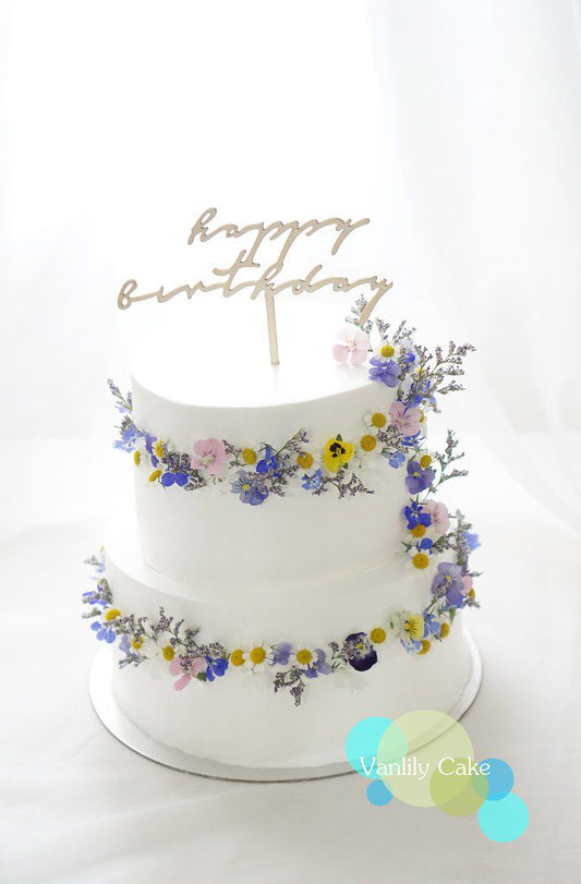 Vanlily Cake 春日花環忌廉蛋糕系列,展示簡約白抹面蛋糕圍繞著彩色鮮花花環,搭配「Happy Birthday」或「Bride to Be」金色插牌,展現清新浪漫的森林系質感。