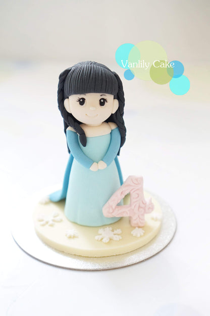 Vanlily Cake 冰雪公主城堡造型蛋糕，雙層藍色設計點綴雪花裝飾、城堡尖塔與可愛公主公仔，並標示客製化姓名，適合兒童慶生派對。