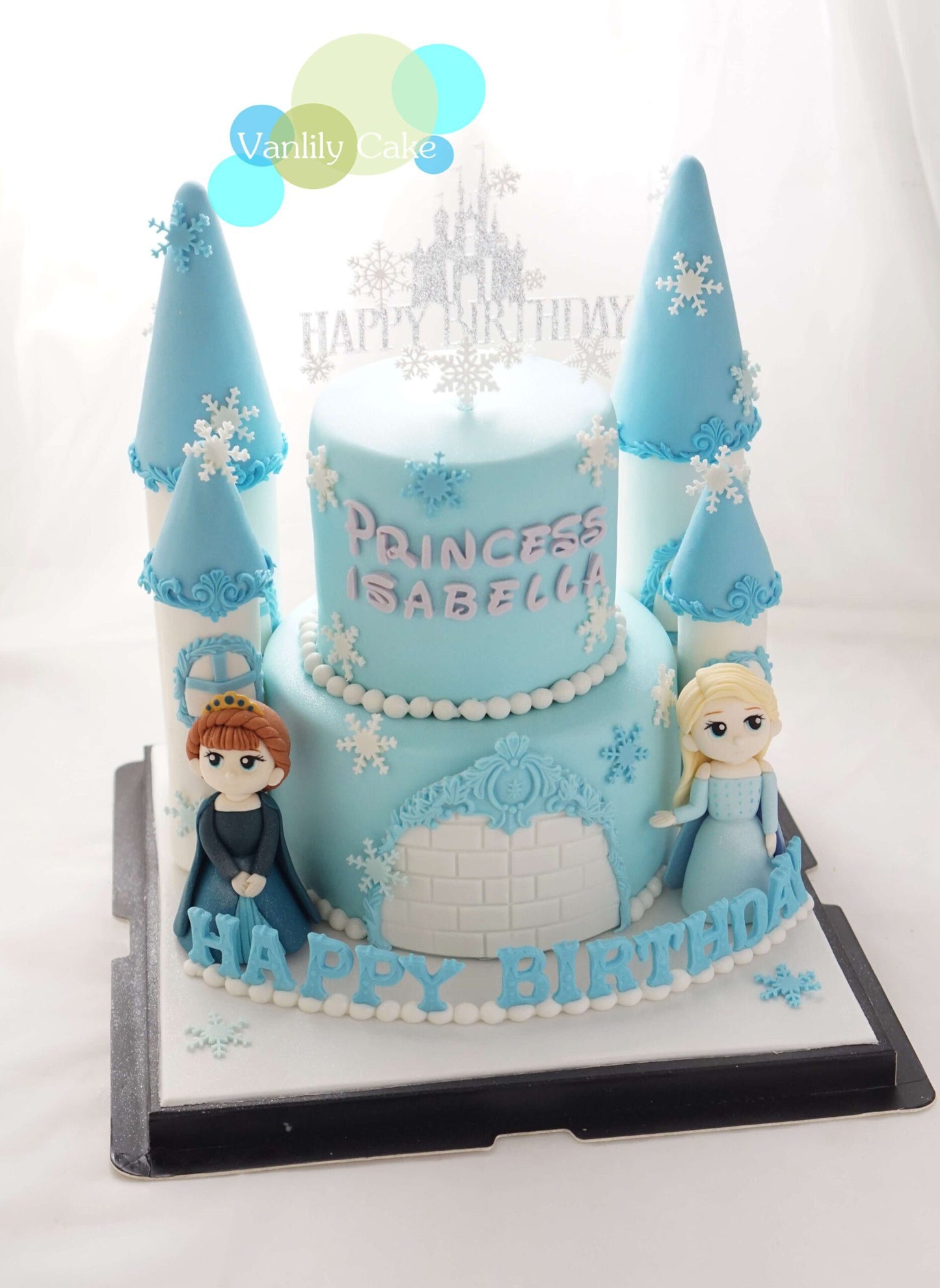 Vanlily Cake 冰雪公主城堡造型蛋糕，雙層藍色設計點綴雪花裝飾、城堡尖塔與可愛公主公仔，並標示客製化姓名，適合兒童慶生派對。