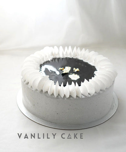 Vanlily Cake 海鹽黑芝麻忌廉蛋糕，展現簡約的灰色抹面與頂部精緻的白色忌廉擠花邊框，中心裝飾有濃郁黑芝麻淋醬與高雅金箔，主打低糖無糖健康配方。
