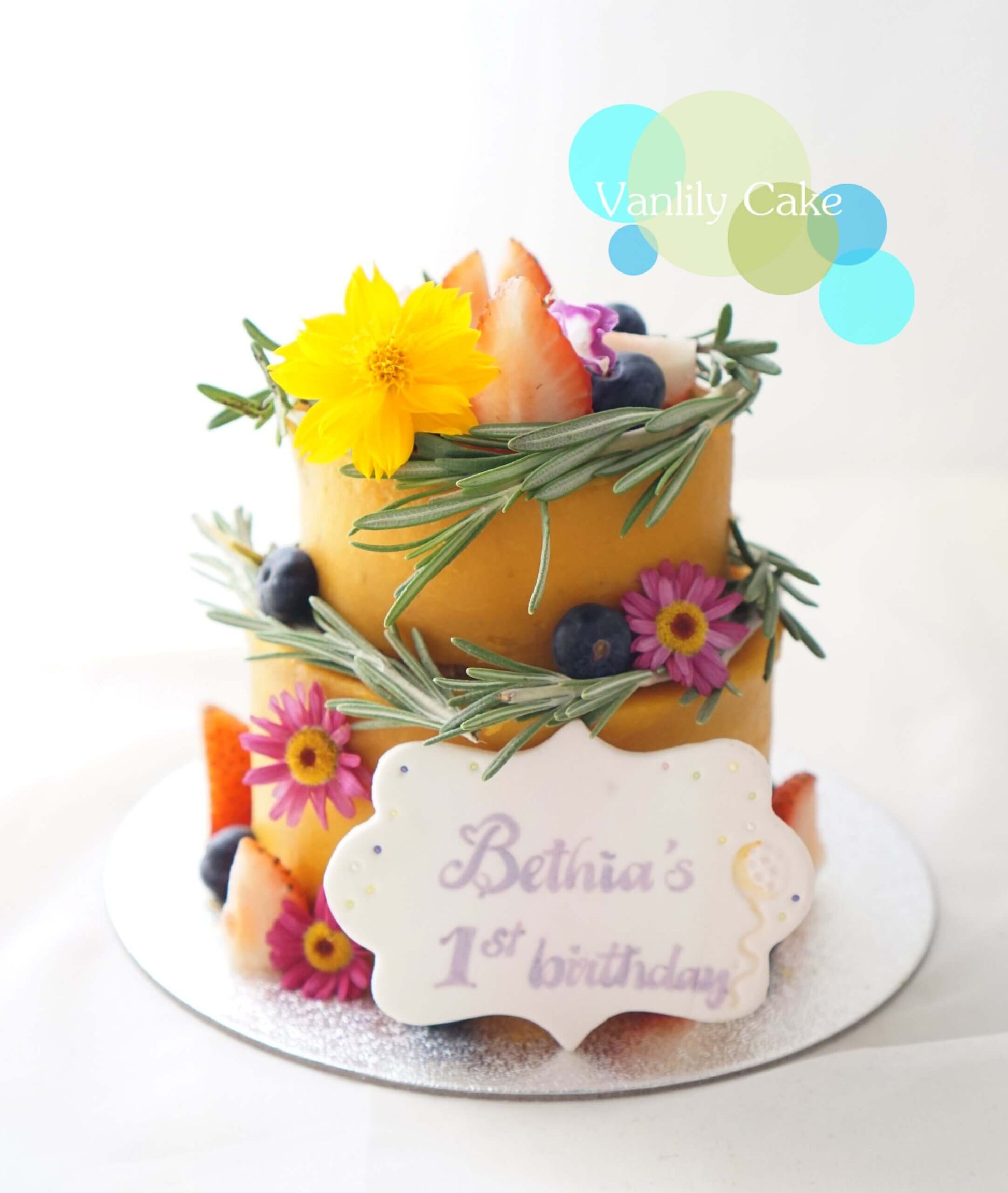 Vanlily Cake 純素香蕉生日蛋糕，展示淮山（白色外層）與蕃薯南瓜（黃色外層）兩款選擇，裝飾有新鮮水果、藍莓與迷迭香，適合一歲寶寶、素食與過敏人士。