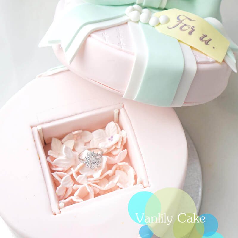 Vanlily Cake 粉色首飾盒翻糖蛋糕，半開的盒蓋露出粉紅花瓣襯托的鑽戒，設計精緻浪漫，適合求婚驚喜。