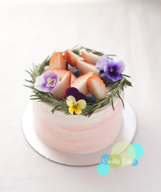 Vanlily Cake 鮮果米蛋糕，展示純白簡約的抹面，頂部裝飾有新鮮草莓、藍莓等時令水果，並點綴綠色香草葉，展現清新自然的視覺美感與手工質感。