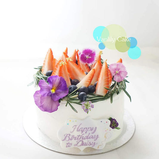 Vanlily Cake 鮮果米蛋糕，展示純白簡約的抹面，頂部裝飾有新鮮草莓、藍莓等時令水果，並點綴綠色香草葉，展現清新自然的視覺美感與手工質感。