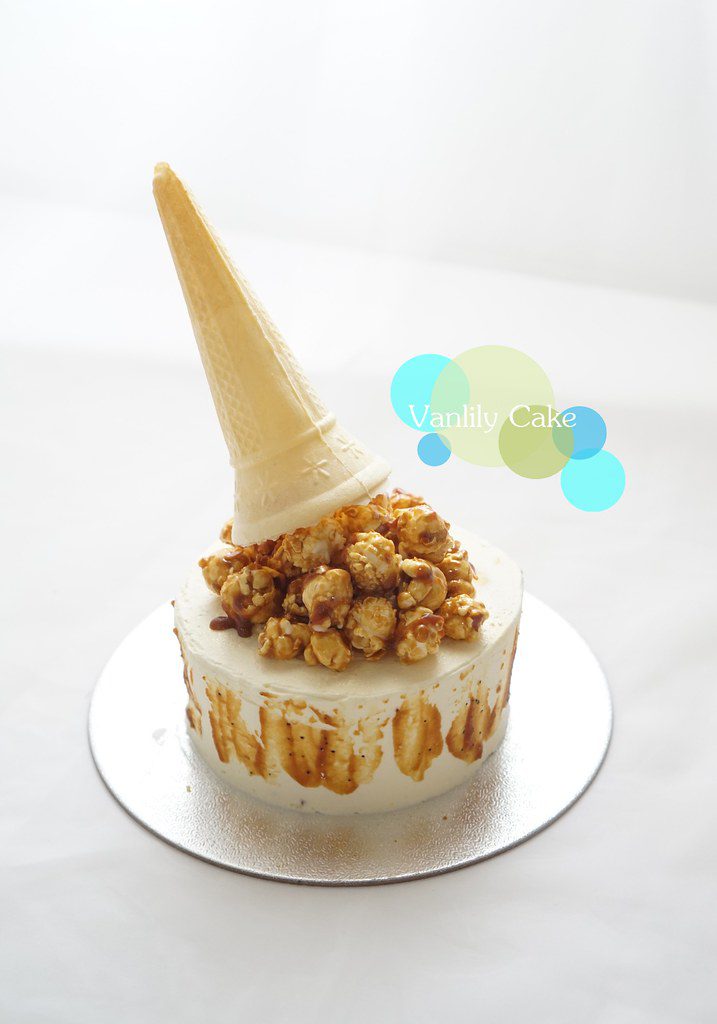 Vanlily Cake 海鹽焦糖流心芝士蛋糕，展示切開後濃郁焦糖醬流出的驚喜瞬間，頂部裝飾有焦糖爆谷與傾倒的威化筒造型，