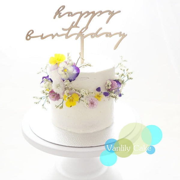 Vanlily Cake 春日花環忌廉蛋糕系列，展示簡約白抹面蛋糕圍繞著彩色鮮花花環，搭配「Happy Birthday」或「Bride to Be」金色插牌，展現清新浪漫的森林系質感。