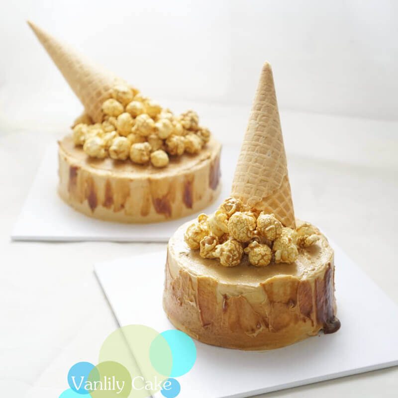 Vanlily Cake 海鹽焦糖流心芝士蛋糕，展示切開後濃郁焦糖醬流出的驚喜瞬間，頂部裝飾有焦糖爆谷與傾倒的威化筒造型，